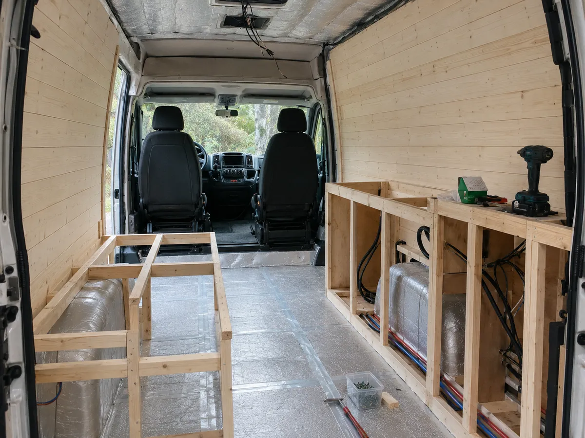 Lege bestelwagen tijdens de ombouw met houten wanden en het begin van het meubelframe.